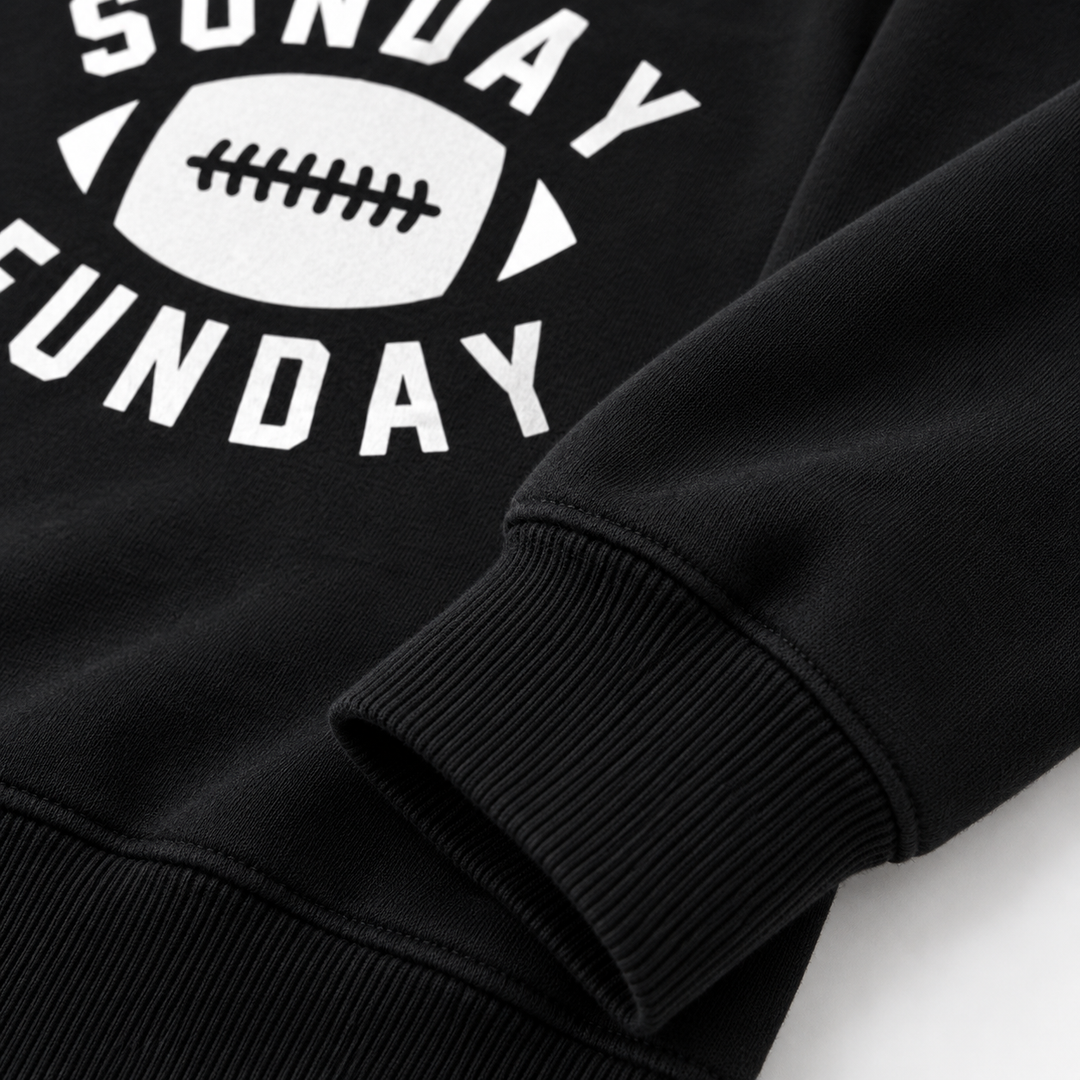 Close-up of black football graphic sweatshirt showing ribbed cuff, hem seam, texture and Sunday Funday print detail up close.