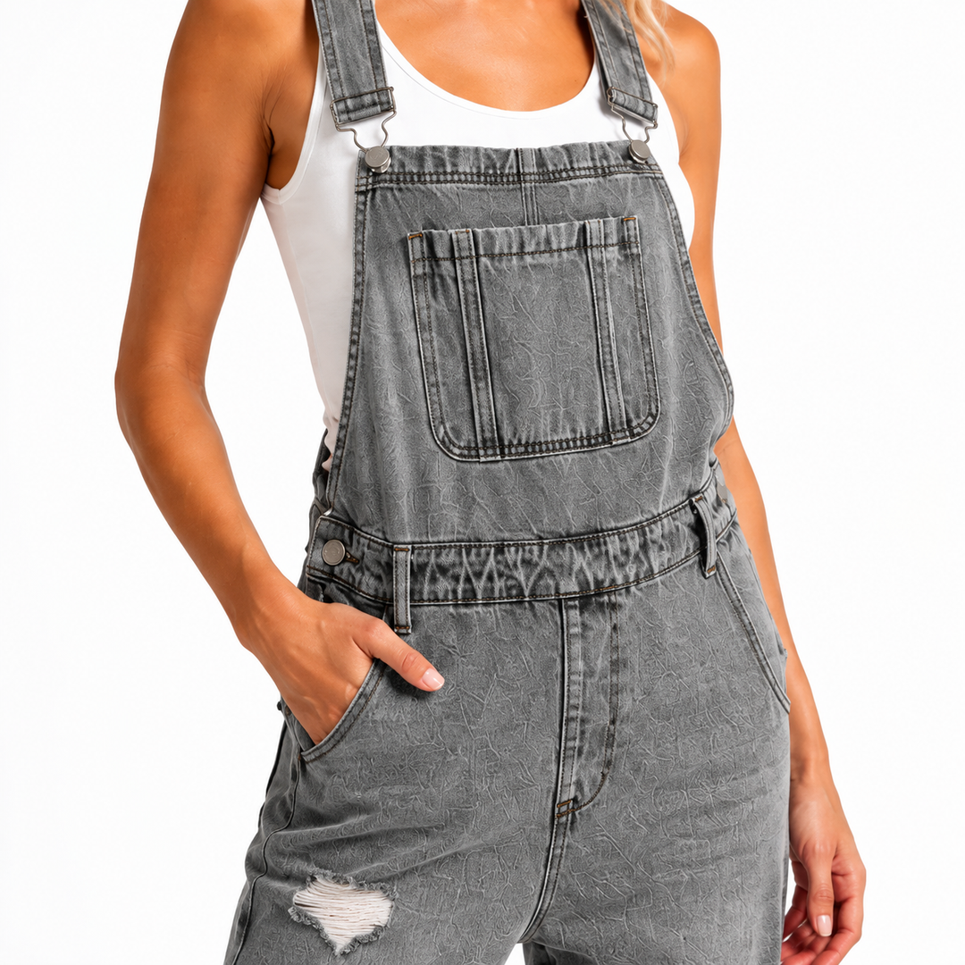 Gray 9145 cropped denim overalls close-up showing adjustable straps, metal parts, bib pocket, stitching and distressed denim.