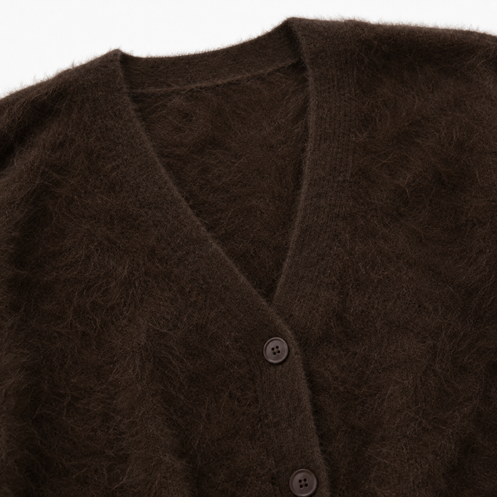 Dark brown fuzzy cardigan close-up showing the V-neck edge, front button placket and textured knit surface in sharp detail.