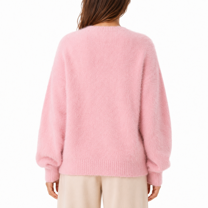 Back view of the light pink fuzzy cardigan, showing the relaxed sweater shape, long sleeves, ribbed cuffs and ribbed lower hem.