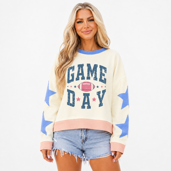 Back view of ivory game day sweatshirt on white, showing blue neckline, sleeve stars, pink cuffs, hem and plain back panel.