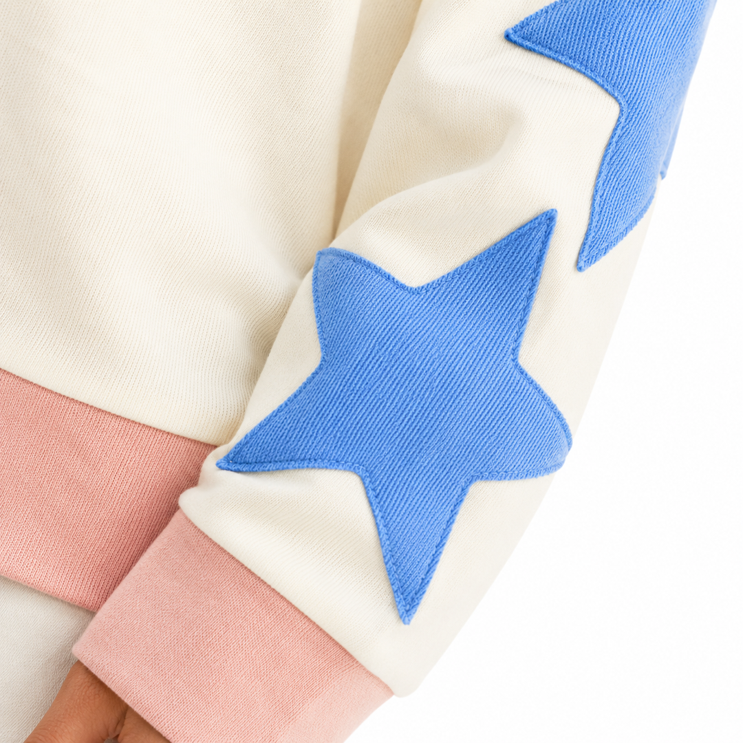 Close-up of blue ribbed neckline and ivory sweatshirt surface, with distressed GAME DAY print details on a white background.