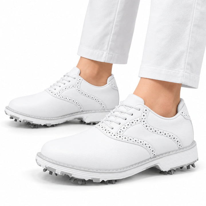 White golf shoes worn with simple white trousers on a white studio background