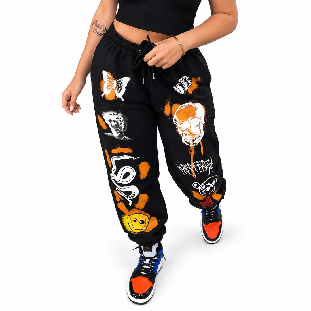 Black drawstring joggers with orange, white and yellow graphics, worn by an adult model