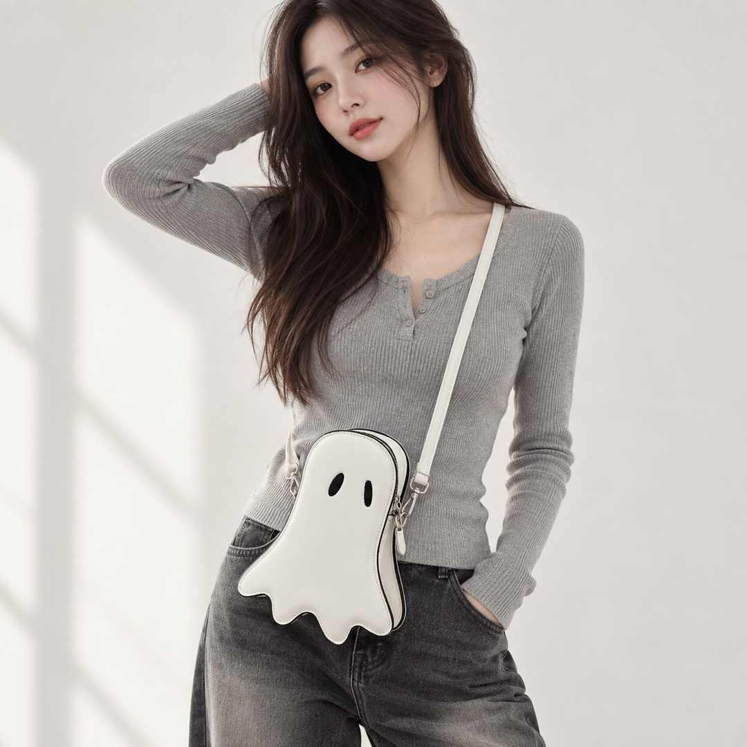 White ghost crossbody bag worn by a model with black oval eyes, contrast piping, zipper and long shoulder strap