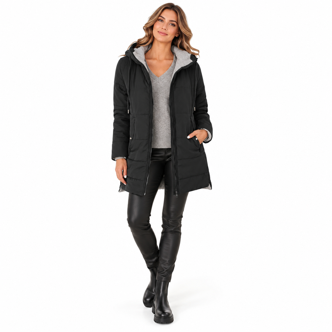 Black hooded jacket on a full-body adult model, worn open over gray knit with black trousers and ankle boots in white studio.