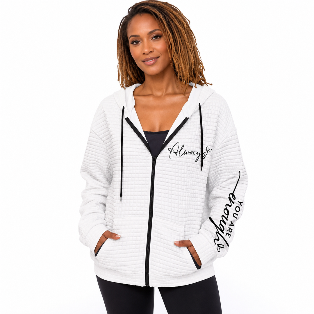 Women's zipper hoodie in white with black zip, hood, pockets and letter graphics on a model against a clean white studio set.