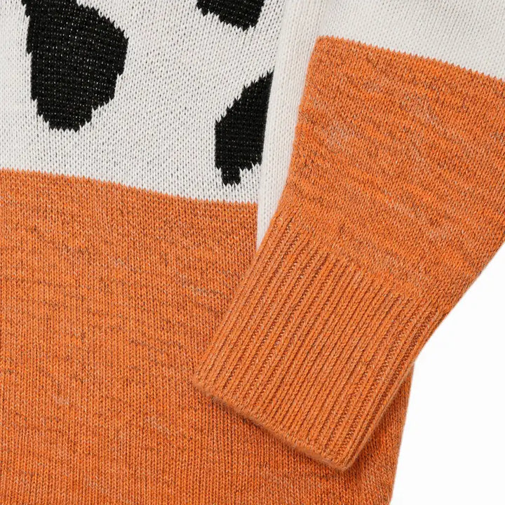 Close view of the orange leopard print sweater knit texture, color-block transition, ribbed cuff and visible construction.