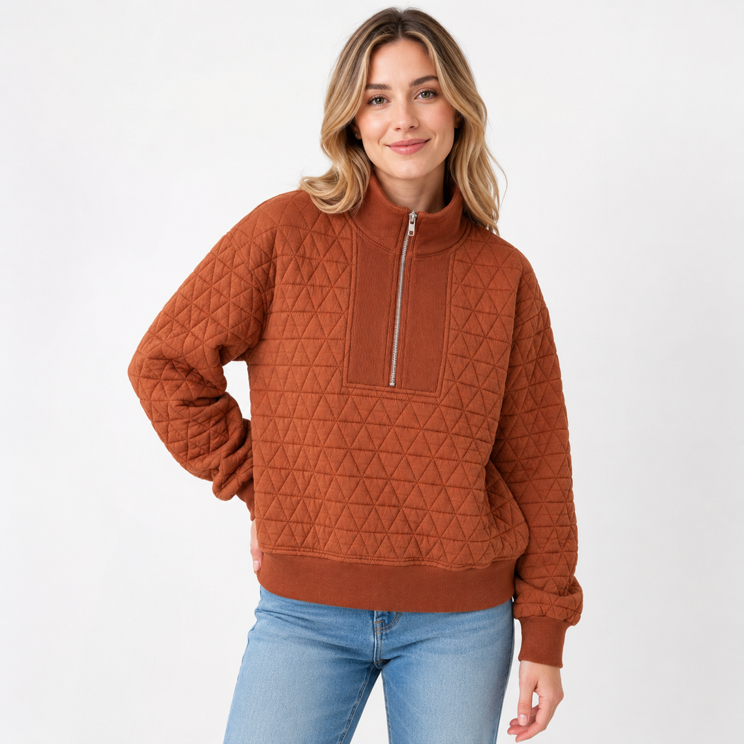 Woman wearing the Caramel quilted half-zip sweatshirt, showing the geometric quilted pattern and ribbed neckline.