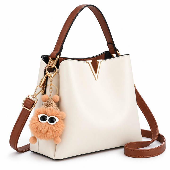 Cream shoulder bag with brown straps and gold V detail, three-quarter view