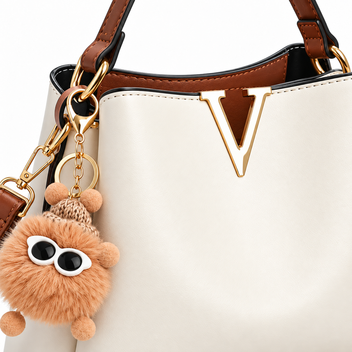 Close-up of cream shoulder bag gold V hardware, stitching and fluffy charm