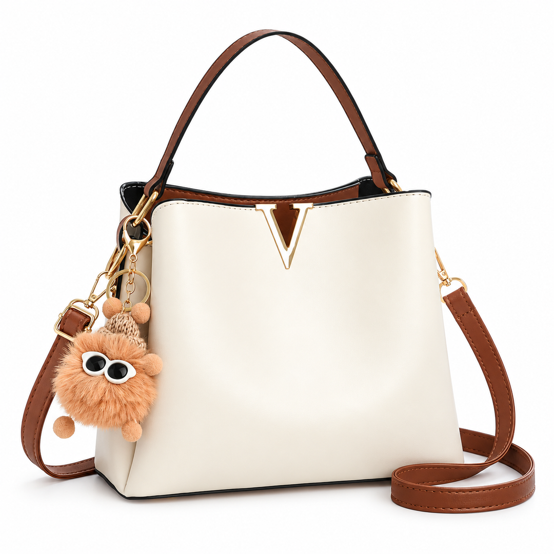 Cream shoulder bag with gold V detail, brown straps and fluffy charm, front view