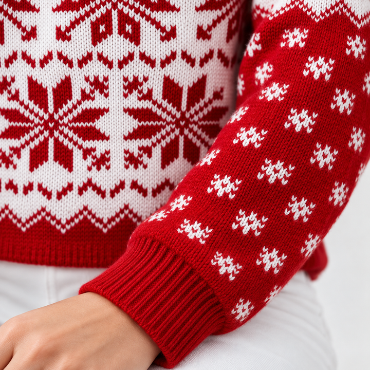 Close-up of the red ribbed cuff and white snowflake motifs on the knit sweater