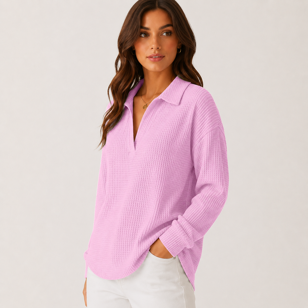 Light pink long sleeve V-neck collared top on a model in side view showing loose drape, waffle texture, cuffs and curved hem.